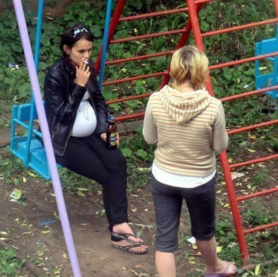 pregnant woman smoking and drinking on swing in park ~ Worst Parents Ever